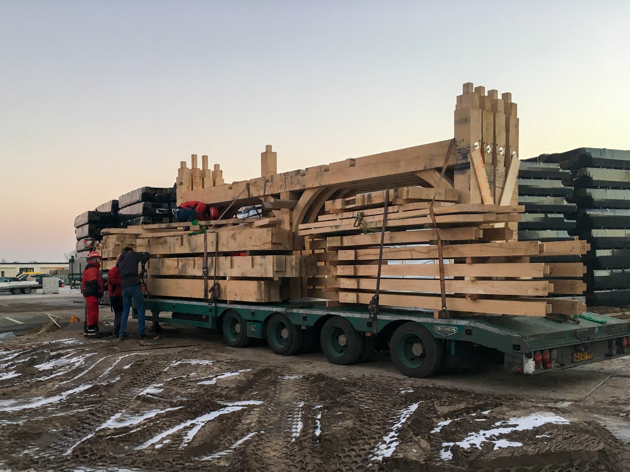 Bouwpakket van een huis met eikenhouten gebinten op een vrachtwagen, aangekomen bij de klant voor levering.